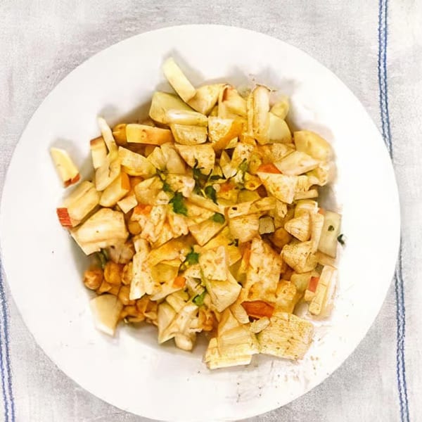 A white plate filled with a colorful Indian dish of chopped vegetables and spices.